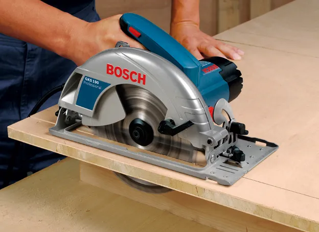 A person cuts plywood using a handheld circular saw.