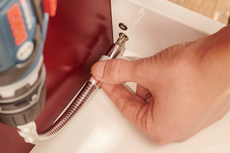 Person using a flexible shaft attachment to drive a screw into a tight space.