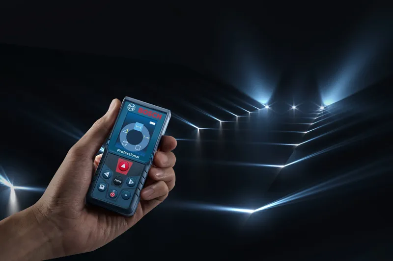 Person holding a laser measure projecting multiple measuring beams across a dark room.