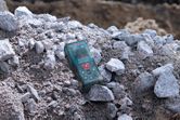 A laser measure resting on a pile of rocks at a construction site.