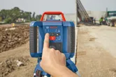 Person operating a laser leveling tool at a construction site.