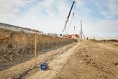 Laser leveling tool set up on a construction site with cranes and earthmoving in the background.