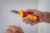 A person uses an insulated utility knife to cut electrical wiring.