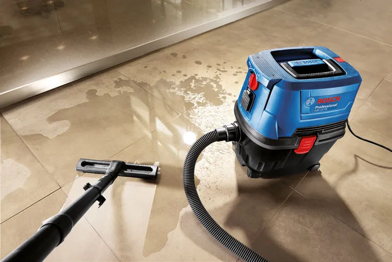 Wet and dry extractor vacuuming water from a tiled floor.