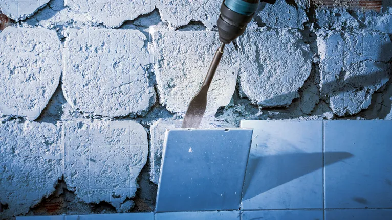 A power tool removes wall tiles with a flat chisel bit.
