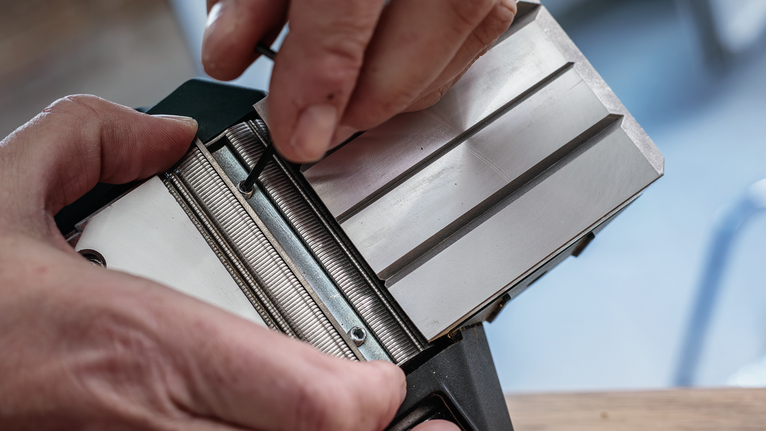 Person adjusts a metal tool component using a hex key.