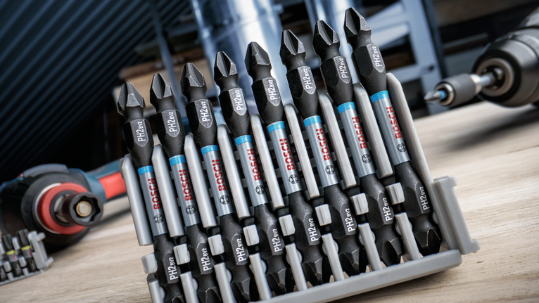 Set of screwdriver bits organized in a plastic holder on a workbench.