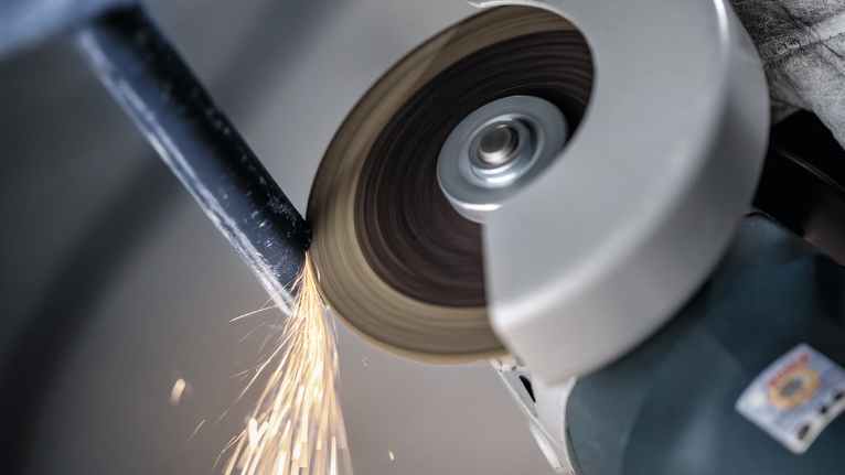 Angle grinder cutting through metal, producing bright sparks.