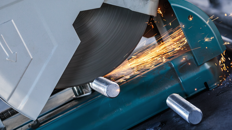 Metal cut-off saw slicing through a steel rod with sparks flying.