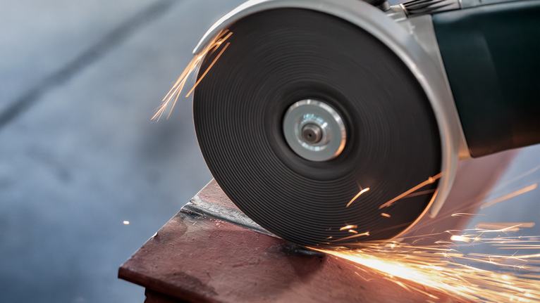 Angle grinder cutting metal, generating sparks.
