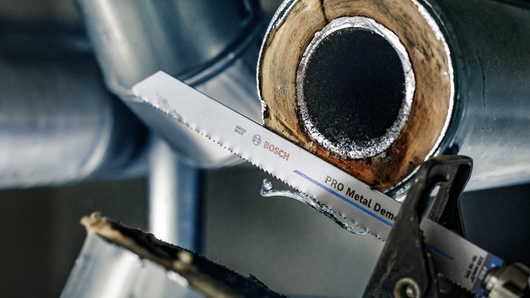 Reciprocating saw blade cutting through a metal pipe.