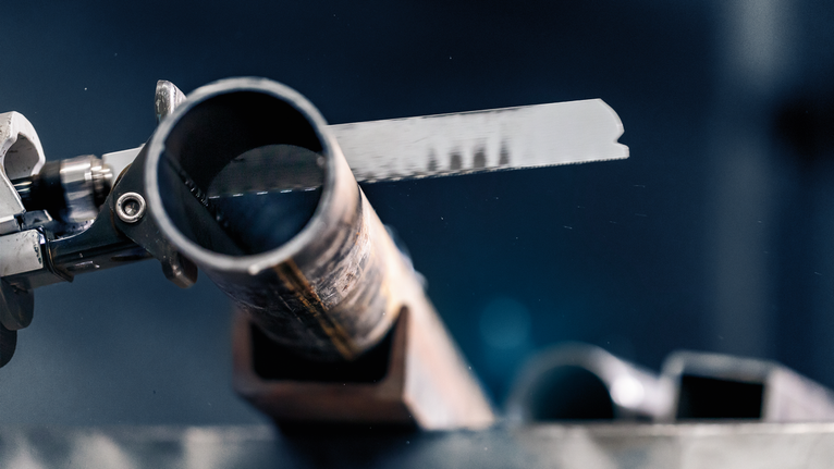 Metal cutting saw blade slicing through a steel pipe.