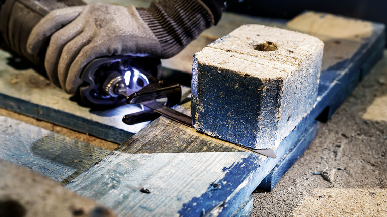 Person wearing safety equipment cuts metal on a wooden pallet with a power tool.