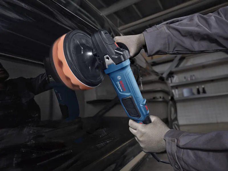 A person wearing safety equipment polishes a car door with a power polisher.