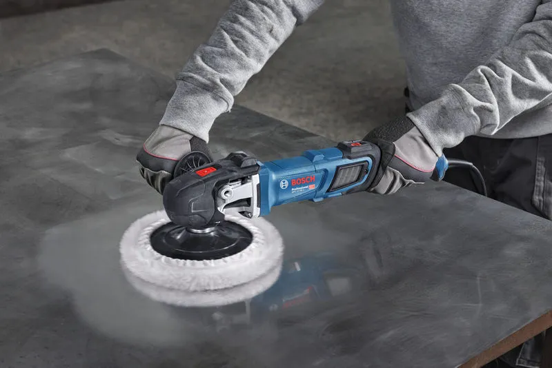 A person wearing safety equipment polishes a metal sheet using a power polisher.