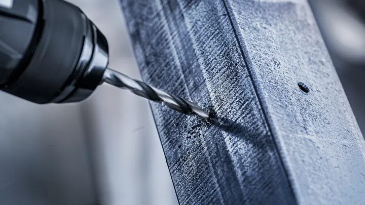 Drill making a hole in a metal beam.