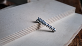 Straight router bit resting on stacked plywood boards.