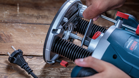 Person using a power tool on a wooden surface.
