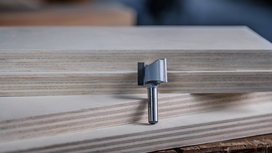 Router bit standing upright on stacked plywood boards.