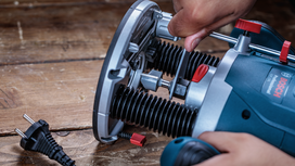 Person adjusts a power tool on a wooden workbench.