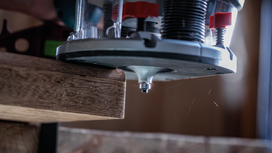 Wood router trimming the edge of a wooden board in a workshop.