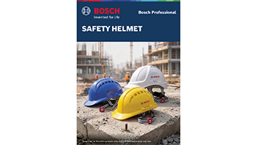 Three safety helmets in blue, white, and yellow are placed on a construction site with buildings under construction in the background.